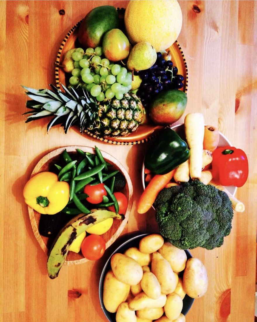 Bowls of fruit and vegetables for a handling session: a pineapple, mangoes, grapes, a melon, pears, sugar snap peas, peppers, tomatoes, carrots, parsnips, broccoli and new potatoes.